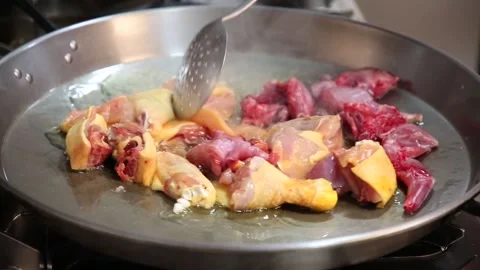 Frying free-range chicken meat on the fire. chicken meat to prepare paella Stock Footage 153274352
