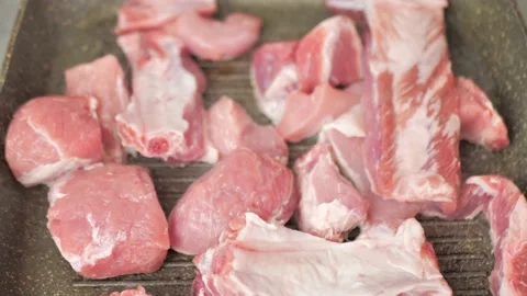 Frying fresh pieces of pork on a grill pan, with the addition of salt Stock Footage 219748112