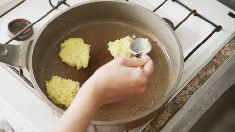 Frying fresh zucchini potato pancakes on gas stove pan in kitchen Stock Footage 333699072