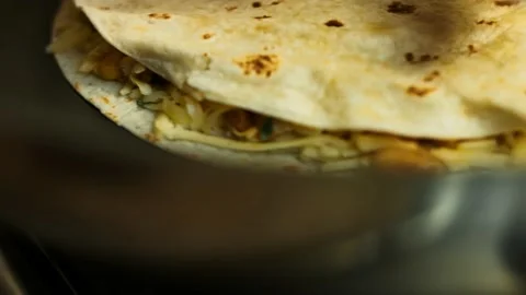 Frying a freshly wraped vegetable quesadilla on a frying pan. Process of making Stock Footage 151295204