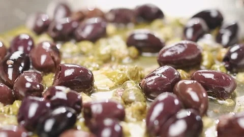 Frying garlic, capers, anchovy fillets and olives in a frying pan. Stock Footage 154938418