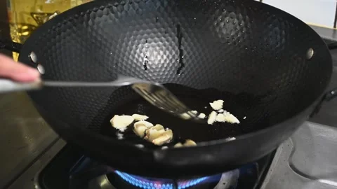 Frying Garlic to Release Its Aroma in a Black Pan Stock Footage 346488349