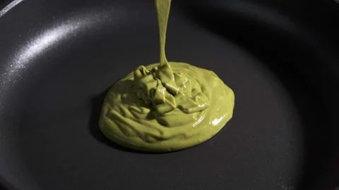 Frying green matcha pancake in black frying pan. Vegan cooking concept. Stock Footage 169444041