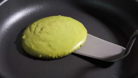Frying green matcha pancake in frying pan. Vegan cooking concept. Video stock 169443489