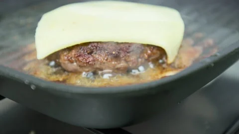 Frying on a grilling pan a beef steak with a cheese on top for a burger in 4K. Stock Footage 153757304