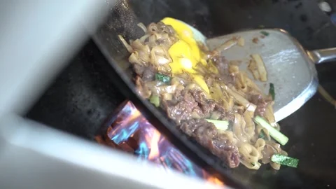 Frying the kwetiaw in a frying pan while stirring Stock Footage 265934433