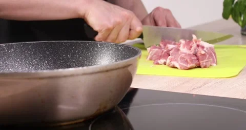 Frying meat. a man cuts the meat into pieces and puts it in a frying pan. Stock Footage 245204560