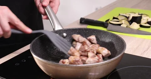 Frying meat. a man stirs pieces of meat in a frying pan with a spatula. Stock Footage 245204450