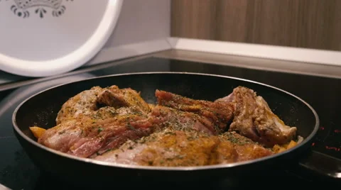 Frying meat in a pan on an electric stove Stock Footage 62066344