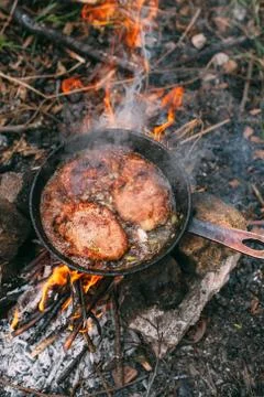 Frying meat in a pan over an open fire with leek. Steak in a pan on a fire. C Stock Photos