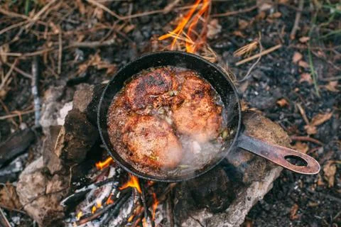 Frying meat in a pan over an open fire with leek. Steak in a pan on a bonfire Stock Photos