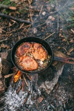 Frying meat in a pan over an open fire with leek. Steak in a pan on a fire. C Stock Photos