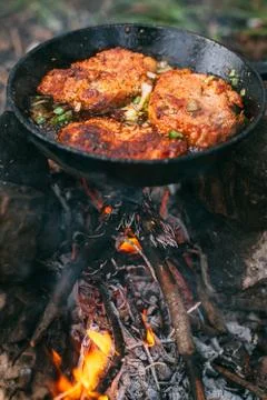 Frying meat in a pan over an open fire with leek. Steak in a pan on a fire. C Stock Photos