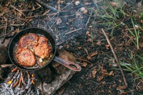 Frying meat in a pan over an open fire with leek. Steak in a pan on a fire. C Stock Photos