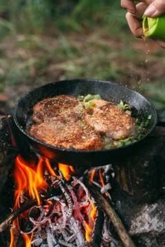 Frying meat in a pan over an open fire with leek. Steak in a pan on a fire. C Stock Photos