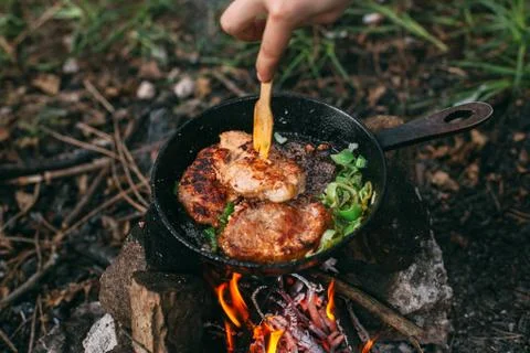 Frying meat in a pan over an open fire with leek. Steak in a pan on a fire. C Stock Photos