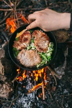 Frying meat in a pan over an open fire with leek. Steak in a pan on a fire. C Stock Photos
