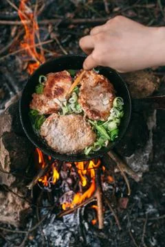 Frying meat in a pan over an open fire with leek. Steak in a pan on a fire. C Stock Photos
