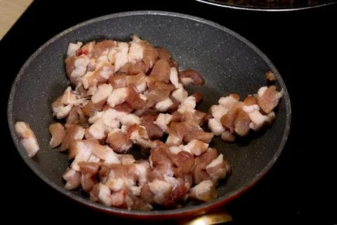 Frying meat in a pan, pan-fried bacon, raw bacon fried in a pan for pierogi.. Stock Photos