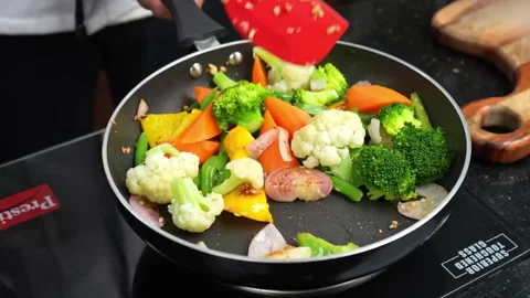 Frying Mixed Vegetables in pan on stove in kitchen room Video stock 286854772
