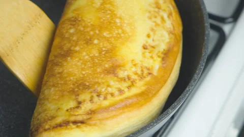 Frying omelet on frying pan turning with spatula cooking on kitchen gas stove. Stock-Footage 313131269