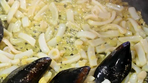 Frying onion and cuttlefish in the pan. Adding mussels Stock Footage 219717150