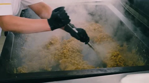 Frying onion in a big pan, close-up. Woman is stirring onion. Steam from the Stock Footage 169465653