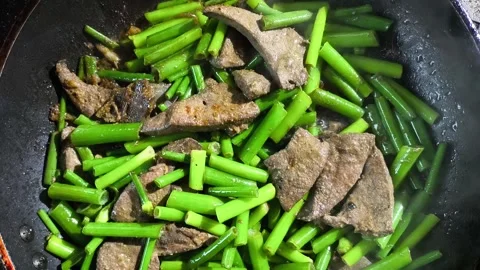 Frying  onion flower stem with pork liver in pan, in door  Chiangmai  Thailand. Stock Footage 300170378