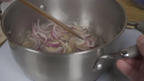 Frying onions in a metal pan Stock Footage 142776963