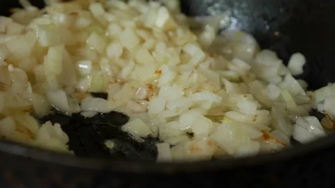 Frying onions in a pan with oil. Stir onion in skillet with wooden spatula. Stock Footage 165872853
