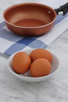 Frying pan and eggs on kitchen counter Stock Photos