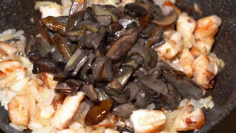 In a frying pan, boiled forest mushrooms are added to fried meat and onions Stock Footage 248228245