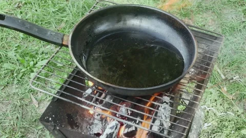 Frying pan with boiling oil on a grate in a clearing Vídeos de archivo 217516819