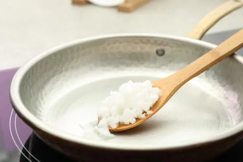 Frying pan with coconut oil on induction stove, closeup. Healthy cooking Stock Photos
