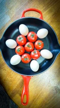 Frying pan with eggs and tomatoes Stock Photos