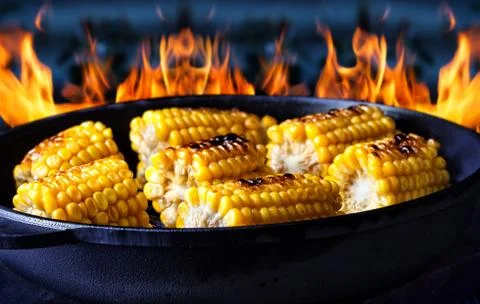 Frying pan with fried corn on fire background Foto stock