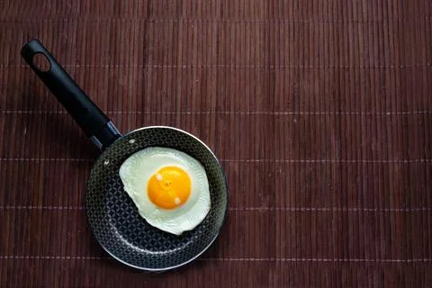 Frying pan with fried egg on a bamboo table Stock Photos