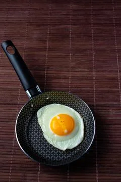 Frying pan with fried egg on a bamboo table Stock Photos