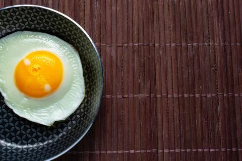 Frying pan with fried egg on a bamboo table Stock Photos