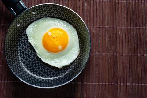 Frying pan with fried egg on a bamboo table Stock Photos