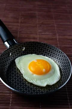Frying pan with fried egg on a bamboo table Stock Photos