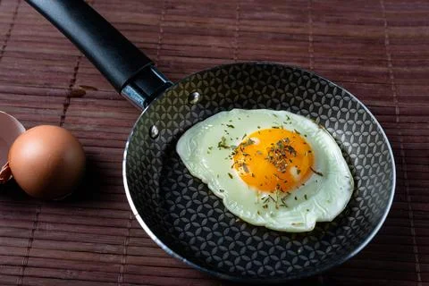 Frying pan with fried egg on a bamboo table Stock Photos