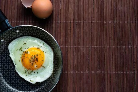 Frying pan with fried egg on a bamboo table Stock Photos