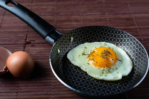 Frying pan with fried egg on a bamboo table Stock Photos