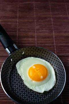 Frying pan with fried egg on a bamboo table Stock Photos