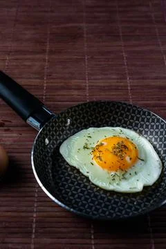 Frying pan with fried egg on a bamboo table Stock Photos