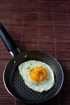 Frying pan with fried egg on a bamboo table Stock Photos