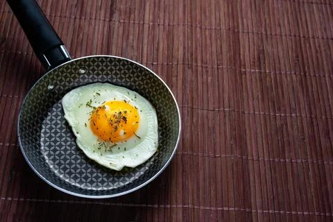 Frying pan with fried egg on a bamboo table Stock Photos