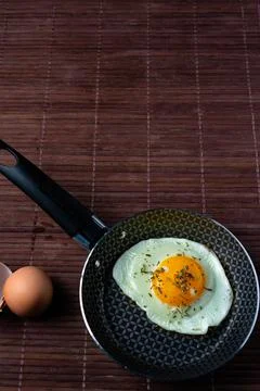 Frying pan with fried egg on a bamboo table Stock Photos