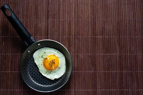 Frying pan with fried egg on a bamboo table Stock Photos